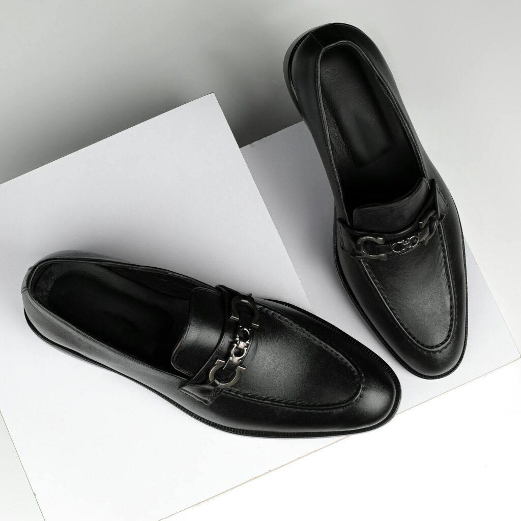 Stylish black leather loafers with chrome detail, perfect for formal occasions.